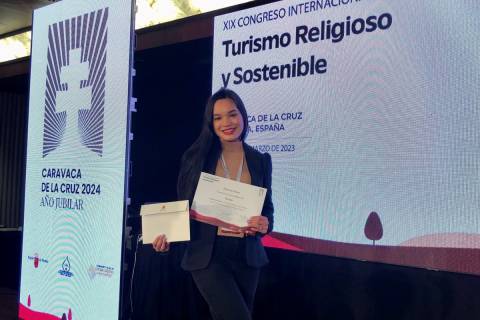 La alumna mostrando el diploma que acredita su premio, durante el Congreso de Turismo Religioso.